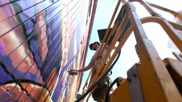 낮은 보기: 젊은 남성 아티스트 벽에 낙서 페인트의 깡통을 그립니다. 그것은 건설 타워에 있어야 한다. 예술에 종사 하는 사람. — 비디오