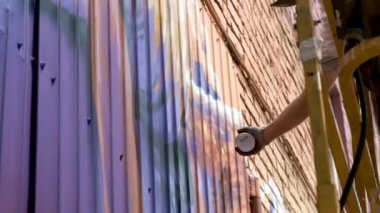 Düşük bir görünümü: bir genç erkek sanatçı bir duvara grafiti boya çizer. Bu bir inşaat kule üzerinde olmalıdır. Sanat yapan bir adam.