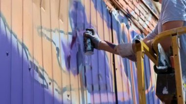 Düşük bir görünümü: bir genç erkek sanatçı bir duvara grafiti boya çizer. Bu bir inşaat kule üzerinde olmalıdır. Sanat yapan bir adam.