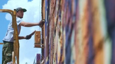 Düşük bir görünümü: bir genç erkek sanatçı bir duvara grafiti boya çizer. Bu bir inşaat kule üzerinde olmalıdır. Sanat yapan bir adam.