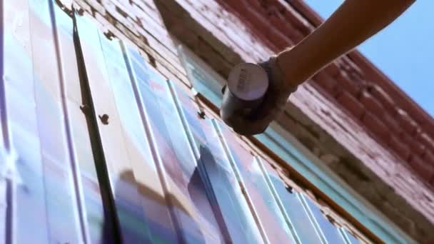 Düşük bir görünümü: bir genç erkek sanatçı bir duvara grafiti boya çizer. Bu bir inşaat kule üzerinde olmalıdır. Sanat yapan bir adam. — Stok video