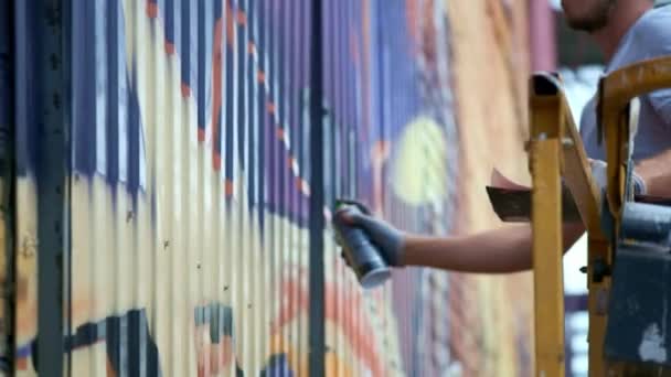 Ein junger Mann mit einer Dose Farbe zeichnet Graffiti an die Wand. Nahaufnahme mit einer Hand. — Stockvideo