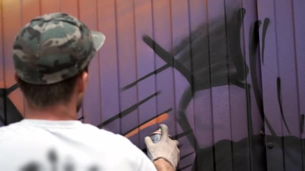 Un jeune homme avec une boîte de peinture dessine des graffitis sur le mur. Une main en gros plan . — Video