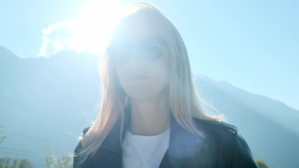 Portret: Mooie blonde meisje in zwarte bril en lederen jas — Stockvideo