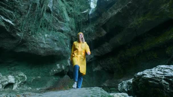 Junge schöne kaukasische Reisende in einem gelben Regenmantel geht durch eine tropische Höhle. auf der Suche nach Abenteuer an exotischen Orten des Planeten. Aktiver Lebensstil — Stockvideo