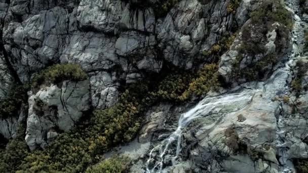 Antenna: hegyi vízesés folyik át a sziklák. Fent a hatalmas hegy-gleccser. — Stock videók
