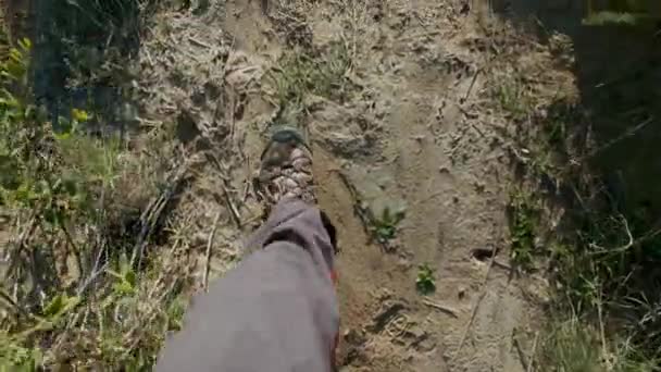 POV: Closeup of hiking boots of an international man. The guy looks at the sea during sunset or sunrise. Hiker goes to the edge of the sandy cliff. Enjoying a vacation trip near the sea — Stock Video