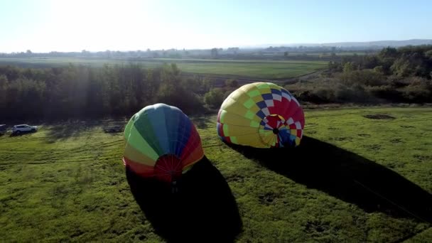 Balão de ar de decolagem ao pôr-do-sol, balões de ar começam a voar do campo de grama no pôr-do-sol de verão, balões de ar no campo com as pessoas na noite de verão, preparação de um balão para o voo — Vídeo de Stock