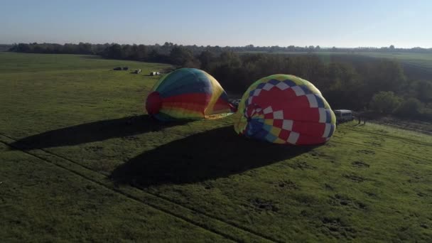 Balão de ar de decolagem ao pôr-do-sol, balões de ar começam a voar do campo de grama no pôr-do-sol de verão, balões de ar no campo com as pessoas na noite de verão, preparação de um balão para o voo — Vídeo de Stock