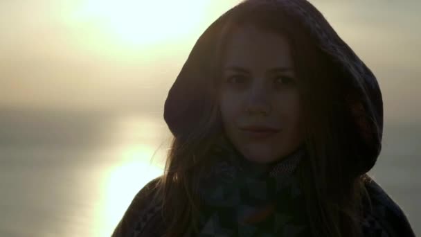 Portret van de jonge vrouw lachend met rode haren waait in de wind op zoek bij zonsondergang over de oceaan meisje dragen gele regenjas wandelen in Schotland Slow Motion close-up — Stockvideo