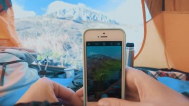 Kamp kadın ayakları smartphone ile fotoğraf çekici çadırda yalan. Yürüyüş botları rahatlatıcı tatil giyen kız kapatın. POV. Crimea.