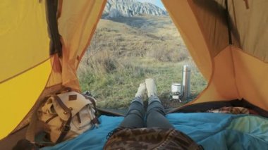 Kamp kadın çadırda yakın yalan yukarı hiking giyen kız ayak boots tatile rahatlatıcı. Büyük Dağları çadır görünümden. Yaşam tarzı yaz aylarında hiking. Dağda yalnız seyahat