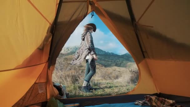 Wanderer attraktive Mädchen stehen in der Nähe des Zelteingangs auf einem Hintergrund von Bergen. genießt Urlaub und Landschaft in den Bergen. das Konzept der Freiheit bei den Abenteuern in den Bergen. — Stockvideo