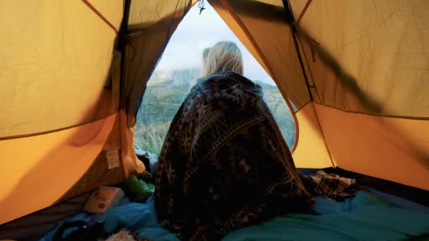 美しい金髪の若い女性は、テント キャンプだけで大きな山に入力します。山の中で孤独で自由の概念。ポンチョを着ています。クリミア半島. — ストック動画