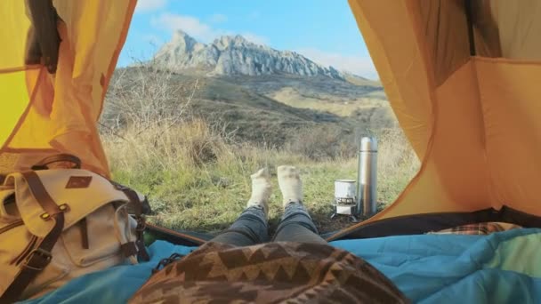 Camping kvinnan ligga i tält nära upp flicka fötter bär Fotvandring stövlar avkopplande semester. Från tält med utsikt över de stora bergen. Vandring livsstil under sommaren. Reser ensam i bergen — Stockvideo