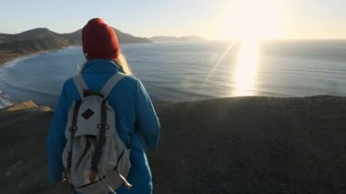 genç çekici kız uzun yürüyüşe çıkan kimse kumlu çıkıntıları veya deniz cliff gider. Ellerini yukarı yükseltir, altın gündoğumu veya günbatımı görünüyor. Başarı duygusu sahiptir. Yüksek bir güzel dağda tırmanıyor.
