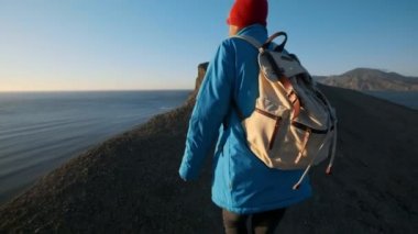 genç çekici kız uzun yürüyüşe çıkan kimse kumlu çıkıntıları veya deniz cliff gider. Ellerini yukarı yükseltir, altın gündoğumu veya günbatımı görünüyor. Başarı duygusu sahiptir. Yüksek bir güzel dağda tırmanıyor.