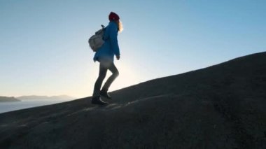 genç çekici kız uzun yürüyüşe çıkan kimse kumlu çıkıntıları veya deniz cliff gider. Ellerini yukarı yükseltir, altın gündoğumu veya günbatımı görünüyor. Başarı duygusu sahiptir. Yüksek bir güzel dağda tırmanıyor.