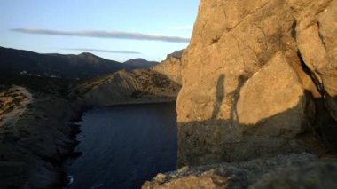siluetleri çiftlerin sarılma. Siluet deniz günbatımı sırasında bir kaya üzerinde. Birlikte seyahat ve tatil keyfini çıkarın. Dostluk ve sevgi kavramı.