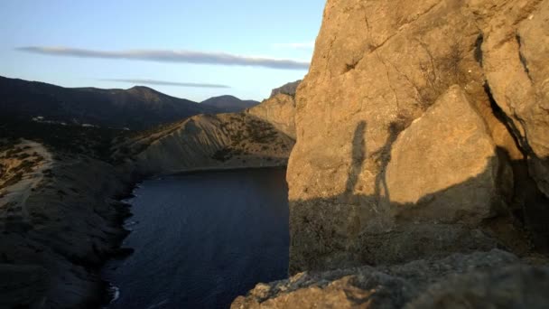 Siluetter av par som kramas. Silhouette på en sten i havet under solnedgången. Njut av din semester och resa tillsammans. Begreppet vänskap och kärlek. — Stockvideo