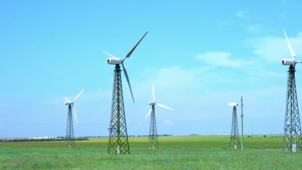 Mavi gökyüzü karşı bir yeşil çimenlerin üzerinde bir çölde eski rüzgar jeneratörleri — Stok video