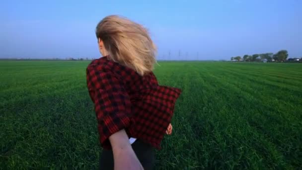 Sígueme, jovencita feliz corriendo a través de un campo de trigo verde joven al atardecer, cámara lenta, destello de lente — Vídeos de Stock