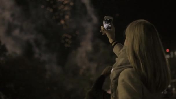 Chica disparando el saludo en el teléfono inteligente. chica joven fotografía fuegos artificiales en el teléfono inteligente. Vacaciones en la ciudad, el cumpleaños de la ciudad . — Vídeo de stock