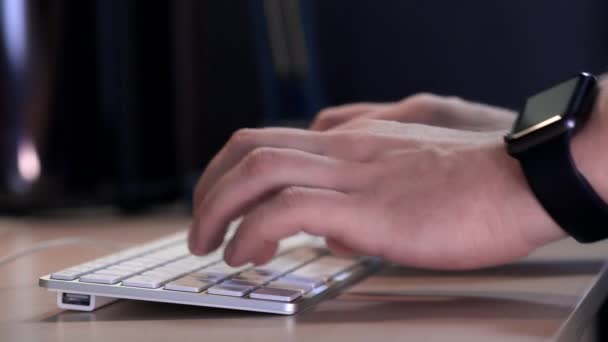 Mannelijke manager te typen op het toetsenbord in het kantoor in de avond. Een slimme horloge wordt gedragen aan de kant. Close-up. — Stockvideo