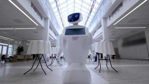 Современные роботизированные технологии. Робот смотрит в камеру на человека. Портрет робота, поворачивает голову. Белый современный робот на выставке новых технологий — стоковое видео