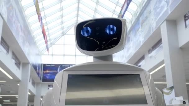 Tecnologías robóticas modernas. El robot mira a la cámara a la persona. Retrato de un robot, gira la cabeza. Robot blanco moderno en la exposición de las nuevas tecnologías — Vídeo de stock