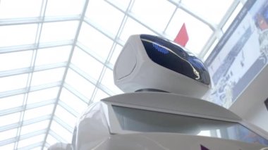Sibernetik sistem bugün. Modern Robotik teknolojiler. Bir robot portresini başını dönüyor, ellerini yukarı yükseltir. Beyaz modern robot yeni teknolojilerin sergisinde