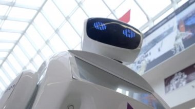 Sibernetik sistem bugün. Modern Robotik teknolojiler. Bir robot portresini başını dönüyor, ellerini yukarı yükseltir. Beyaz modern robot yeni teknolojilerin sergisinde