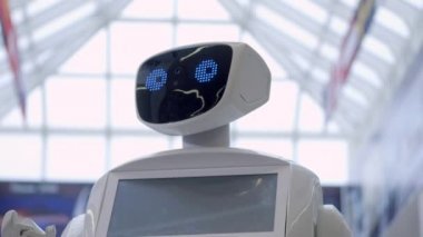 Sibernetik sistem bugün. Modern Robotik teknolojiler. Bir robot portresini başını dönüyor, ellerini yukarı yükseltir. Beyaz modern robot yeni teknolojilerin sergisinde