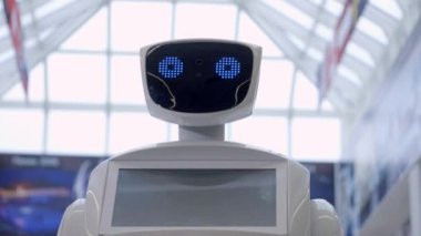 Sibernetik sistem bugün. Modern Robotik teknolojiler. Bir robot portresini başını dönüyor, ellerini yukarı yükseltir. Beyaz modern robot yeni teknolojilerin sergisinde