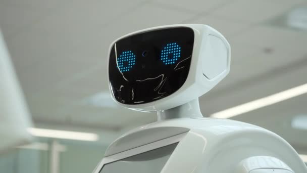 Nowoczesnych technologii robotów. Robot patrzy w kamerę na osobę. Portret robota, odwraca głowę. Białe nowoczesne robot na wystawie nowe technologie. — Wideo stockowe