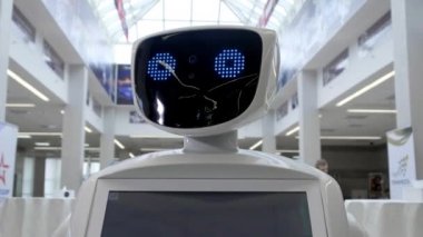 Modern Robotik teknolojiler. Robot kişi kameraya bakar. Bir robot portresini kafasını döner. Beyaz modern robot yeni teknolojilerin sergisinde.