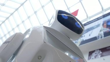 Sibernetik sistem bugün. Modern Robotik teknolojiler. Bir robot portresini başını dönüyor, ellerini yukarı yükseltir. Beyaz modern robot yeni teknolojilerin sergisinde