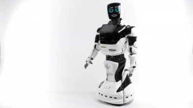 Modern Robotik teknolojiler. Parlak Studio robot. Android yükseltir ve beyaz zemin üzerine el düşürür. İyi ve kötü duygular gösterir. Kameraya bakarak