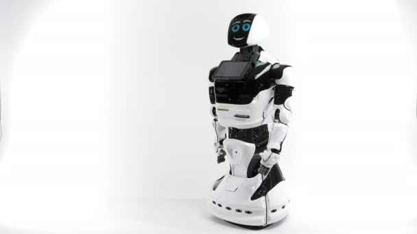 Tecnologías robóticas modernas. Robot en el estudio brillante. Android levanta y baja la mano sobre un fondo blanco. Muestra malas y buenas emociones. Mirando la cámara — Vídeo de stock