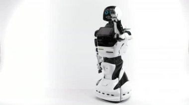 Modern Robotik teknolojiler. Parlak Studio robot. Android yükseltir ve beyaz zemin üzerine el düşürür. İyi ve kötü duygular gösterir. Kameraya bakarak