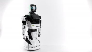 Modern Robotik teknolojiler. Parlak Studio robot. Android yükseltir ve beyaz zemin üzerine el düşürür. İyi ve kötü duygular gösterir. Kameraya bakarak