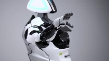 Modern Robotik teknolojiler. Beyaz modern robot parlak bir stüdyoda. Bir tebrik el sallayarak android görüntüleyiciyi selamlıyor. Beyaz zemin üzerinde bir robot gösteri. Burada gelecek.