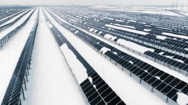 AERIAL: Fotovoltaica en invierno cubierta de nieve. Paneles solares entre las corrientes de nieve, cubiertos de nieve. Fuentes alternativas de energía en los países nórdicos . — Vídeo de stock
