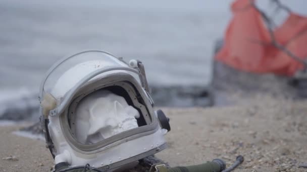 Mrtvý astronaut na planetě. Lebka z hlavy helmu leží na písku u moře. Ustaraný náhodou. — Stock video