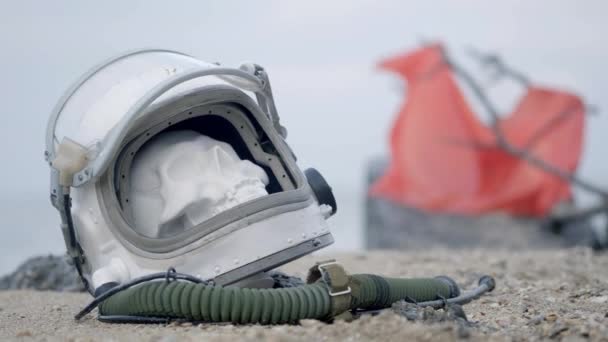 地球上の死んだ宇宙飛行士 ヘルメットの頭から頭蓋骨は海で砂の上にあります 事故に悩まされて — ストック動画