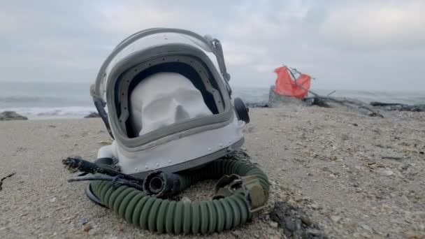 Hlavu mrtvého kosmonaut leží na písku u moře. Astronaut havaroval na své kosmické lodi. Oblačné počasí, vítr fouká — Stock video