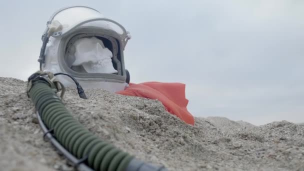 Голова мертвого космонавта лежить на піску біля моря. Астронавт розбився на своєму космічному кораблі. Похмура погода, вітер дме — стокове відео