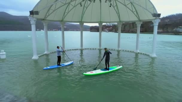 Anapa Rusland - 19.01.2019: Twee renners drijven op de sup surfplanken. Zwemmen tussen de bomen in het oude overstroomd park. Leren surfen. Sup — Stockvideo
