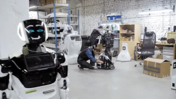 Fábrica para la producción de robots. El ingeniero examina el robot. Crea un nuevo robot en el laboratorio. Repara piezas de robot . — Vídeos de Stock