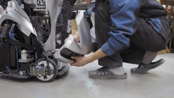 ロボットの生産のための工場。エンジニアは、ロボットを調べます。ラボで新しいロボットを作成します。修理ロボット部品. — ストック動画